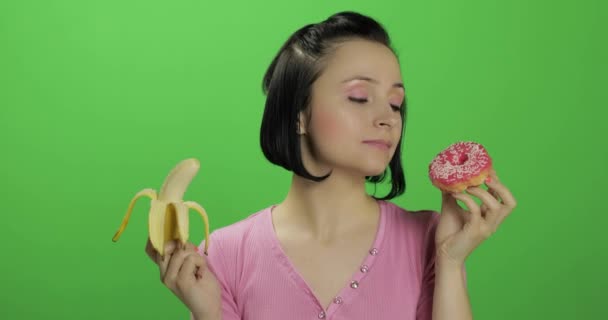 Gesunde Ernährung zu beginnen. Nein zu Junk Food. Wahl zwischen Donut oder Banane — Stockvideo