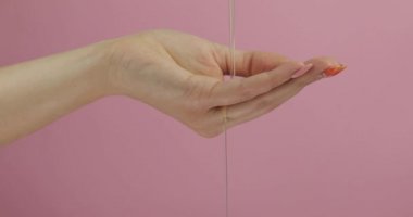 Kadın elinde taze yumurta. Manikür el pembe arka plan üzerinde yumurta sarısı tutar