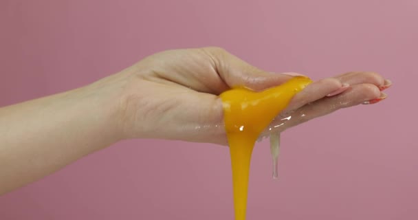 Świeże jajko na rękę kobiety. Manicure ręka trzyma żółtka na różowym tle — Wideo stockowe