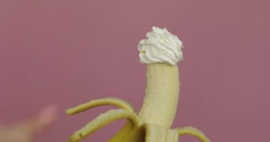 Kadın elinde muzla meyveli krema tutuyor. Parmak kremaya dokunur.