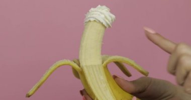 Kadın elinde muzla meyveli krema tutuyor. Parmak kremaya dokunur.