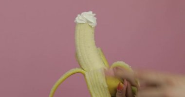 Kadın elinde muzla meyveli krema tutuyor. Parmak kremaya dokunur.