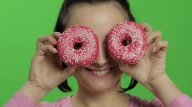 Mutlu güzel genç kız poz ve çörekler ile eğleniyor. Renk anahtarı