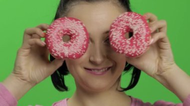 Mutlu güzel genç kız poz ve çörekler ile eğleniyor. Renk anahtarı