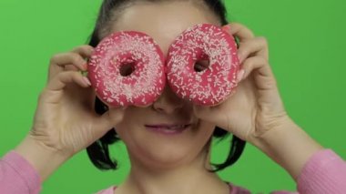 Mutlu güzel genç kız poz ve çörekler ile eğleniyor. Renk anahtarı