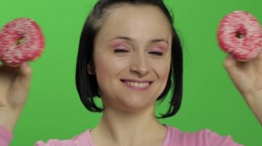 Mutlu güzel genç kız poz ve çörekler ile eğleniyor. Renk anahtarı