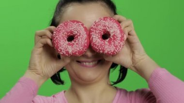 Mutlu güzel genç kız poz ve çörekler ile eğleniyor. Renk anahtarı