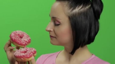 Mutlu güzel genç kız poz ve çörekler ile eğleniyor. Renk anahtarı