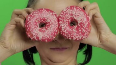 Mutlu güzel genç kız poz ve çörekler ile eğleniyor. Renk anahtarı