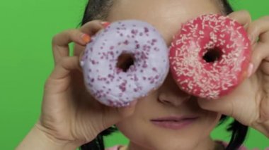 Mutlu güzel genç kız poz ve çörekler ile eğleniyor. Renk anahtarı