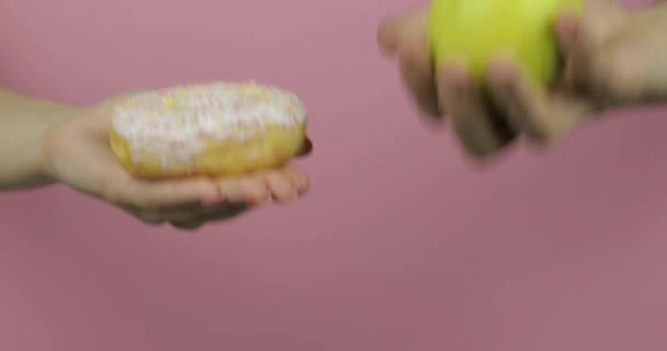 Hands holds donut and apple. Choice donut against apple. Healthy or junk food — Stock Video