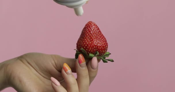 Frau hält Erdbeere in der Hand und drückt Schlagsahne auf die Beere — Stockvideo