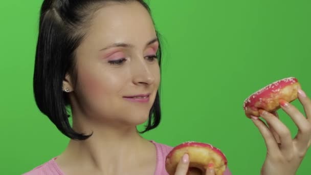Ευτυχισμένο όμορφο νεαρό κορίτσι ποζάρει και να διασκεδάζουν με ντόνατς. Πλήκτρο αποχρώσεων — Αρχείο Βίντεο