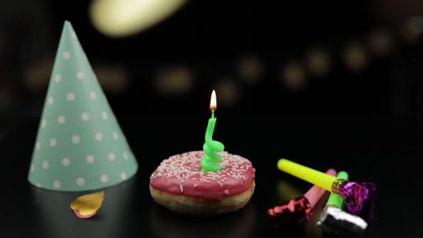 Fiesta. Rosado donut y una vela festiva roja en él. Caída de confeti dorado — Vídeo de stock