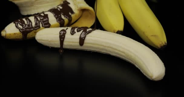 Despeje uma banana com xarope de chocolate escuro derretido. Fundo preto — Vídeo de Stock