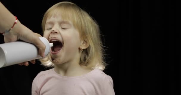 Bambino con la faccia sporca da cioccolato fuso mangia panna montata — Video Stock