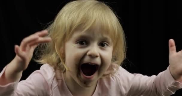 Ребенок с грязным лицом от расплавленного шоколада и взбитых сливок улыбается — стоковое видео
