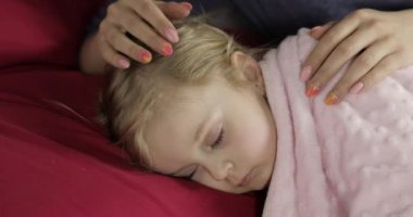 Genç anne uyurken küçük kızına göz kulak oluyor. Yataktaki kız