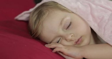 Sevimli bebek evde yatakta uyuyor. Küçük kız sabah ışığında uyku
