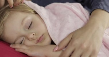 Genç anne uyurken küçük kızına göz kulak oluyor. Yataktaki kız