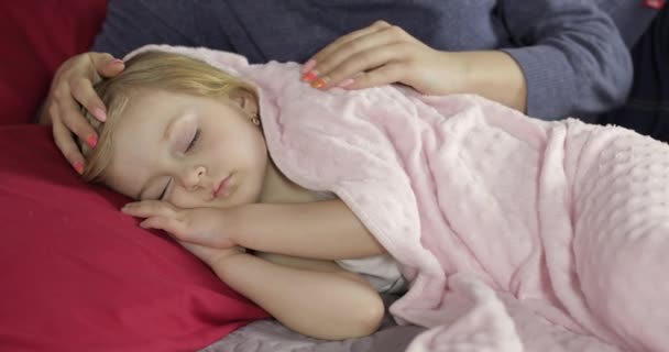 Η νεαρή μητέρα φροντίζει το κοριτσάκι της ενώ κοιμάται. Κορίτσι στο κρεβάτι — Αρχείο Βίντεο