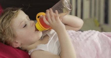 Sevimli bebek kız evde rahat yatakta uyku ve şişe suyu içme