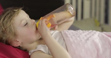 Sevimli bebek kız evde rahat yatakta uyku ve şişe suyu içme