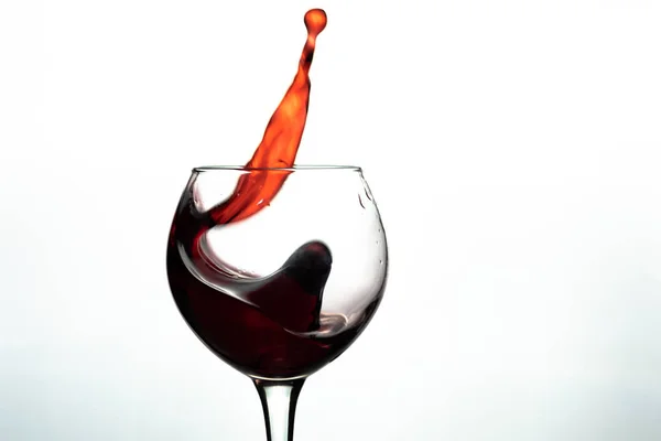 Vino rosso spruzzata in vetro su sfondo bianco — Foto Stock