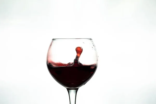 Salpicos de vinho tinto em vidro no fundo branco — Fotografia de Stock