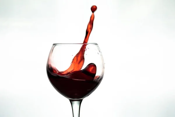 Vino rosso spruzzata in vetro su sfondo bianco — Foto Stock