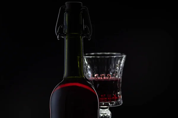 Du vin rose. Vin rouge en bouteille avec verre à vin sur fond sombre. Silhouette — Photo