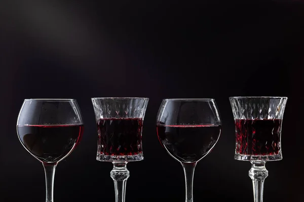 Vino rosato. Vino rosso in quattro bicchieri di vino su sfondo scuro con raggi di luce — Foto Stock