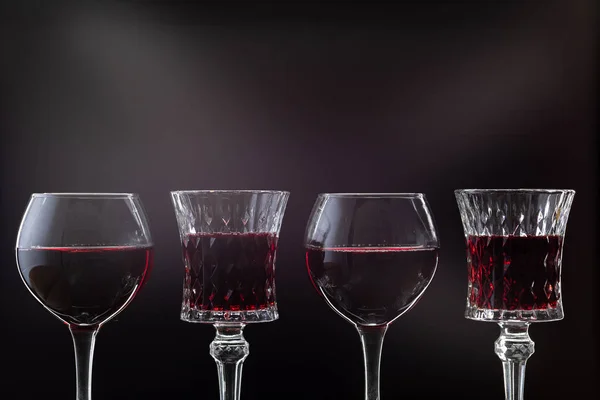 Rose wine. Red wine in four wine glasses over dark background with rays of light