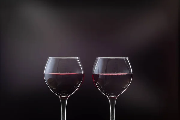 Vino rosato. Vino rosso in due bicchieri di vino su sfondo scuro con raggi di luce — Foto Stock