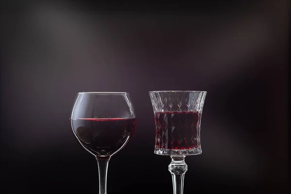 Rosenwein. Rotwein in zwei Weingläsern über dunklem Hintergrund mit Lichtstrahlen — Stockfoto
