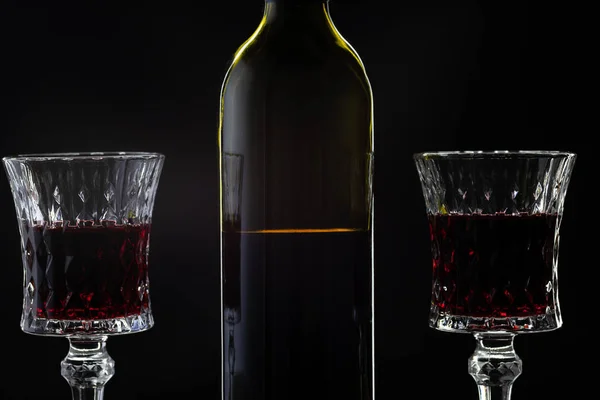 Vinho rosa. Vinho tinto em garrafa com dois copos de vinho sobre fundo escuro — Fotografia de Stock
