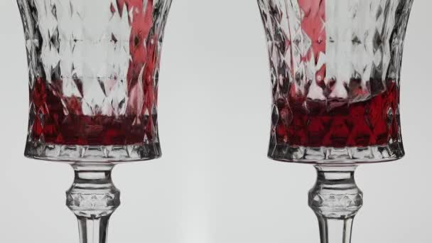 Рожеве вино. Червоне вино наливають у два келихи для вина на білому тлі — стокове відео