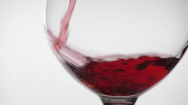 Розовое вино. Красное вино наливают в бокал вина на белом фоне. Медленное движение — стоковое видео