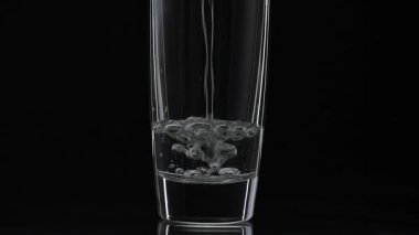 İçki bardağına bir bardak votka döküyorum. Yavaş çekim. Siyah arka plan