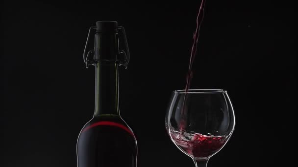 Розовое вино. Красное вино наливают в бокал вина на черном фоне. Медленное движение — стоковое видео