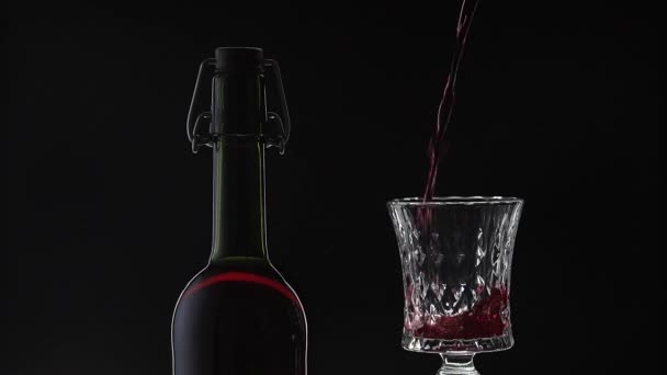 Vino rosato. Vino rosso versare in bicchiere di vino su sfondo nero. Rallentatore — Video Stock