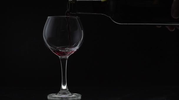 Ροζέ κρασί. Κόκκινο κρασί χύνουμε σε γυαλί κρασιού σε μαύρο φόντο. Αργή κίνηση — Αρχείο Βίντεο