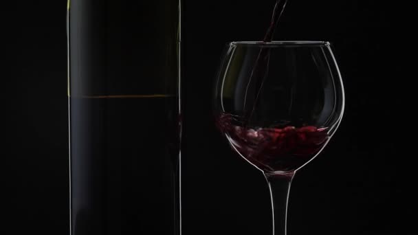 Vino rosato. Vino rosso versare in bicchiere di vino su sfondo nero. Rallentatore — Video Stock