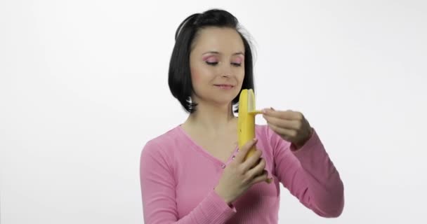Jonge vrouw die bananen eet en zegt lekker. Meisje neemt eerste hap en zeggen wil bijten — Stockvideo