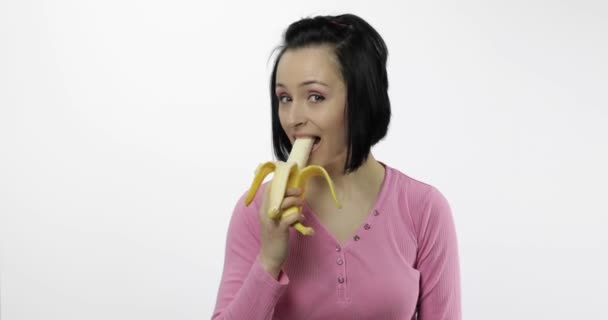 Joven hermosa mujer comiendo plátano grande y fresco sobre fondo blanco — Vídeos de Stock