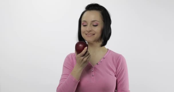 Молодая женщина ест яблоко и говорит: "Ням". Девушка откусывает первый кусок и говорит: — стоковое видео