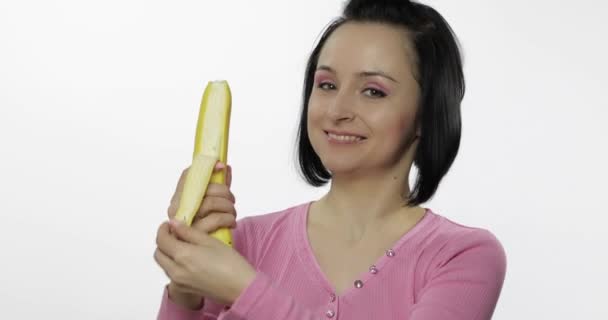 Молодая женщина ест банан и говорит "ням-ням". Девушка откусывает первый кусок и говорит: — стоковое видео