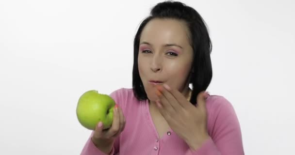 Mladá krásná žena jíst velké, a šťavnaté zelené jablko na bílém pozadí — Stock video