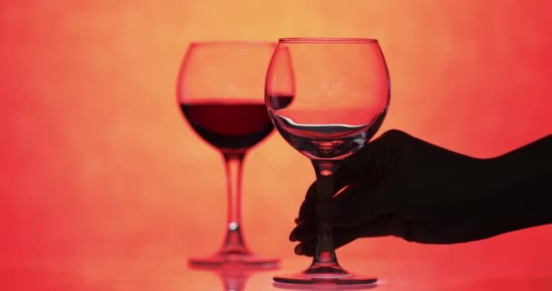 Vino rosa. Vino tinto verter en copa de vino sobre fondo naranja — Vídeo de stock