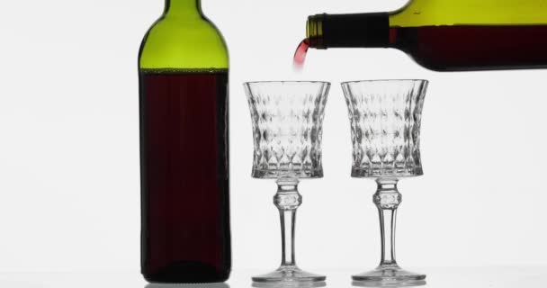 Розовое вино. Красное вино наливают в два бокала вина на белом фоне — стоковое видео